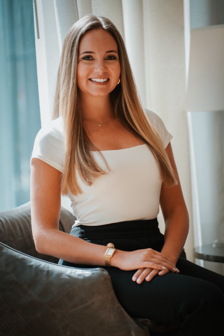 Mason Koski, Atlanta real estate agent, smiling in a white top and black trousers